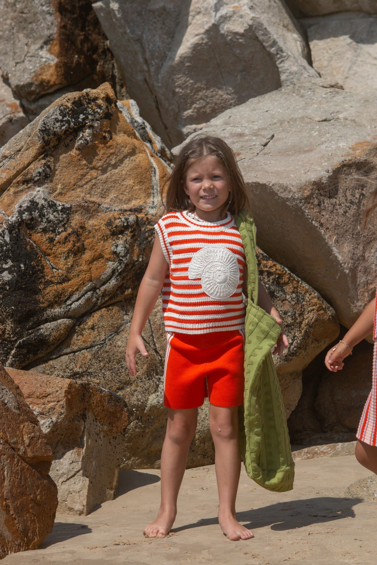 Young girl in a red and white striped vest with a crochet shell.